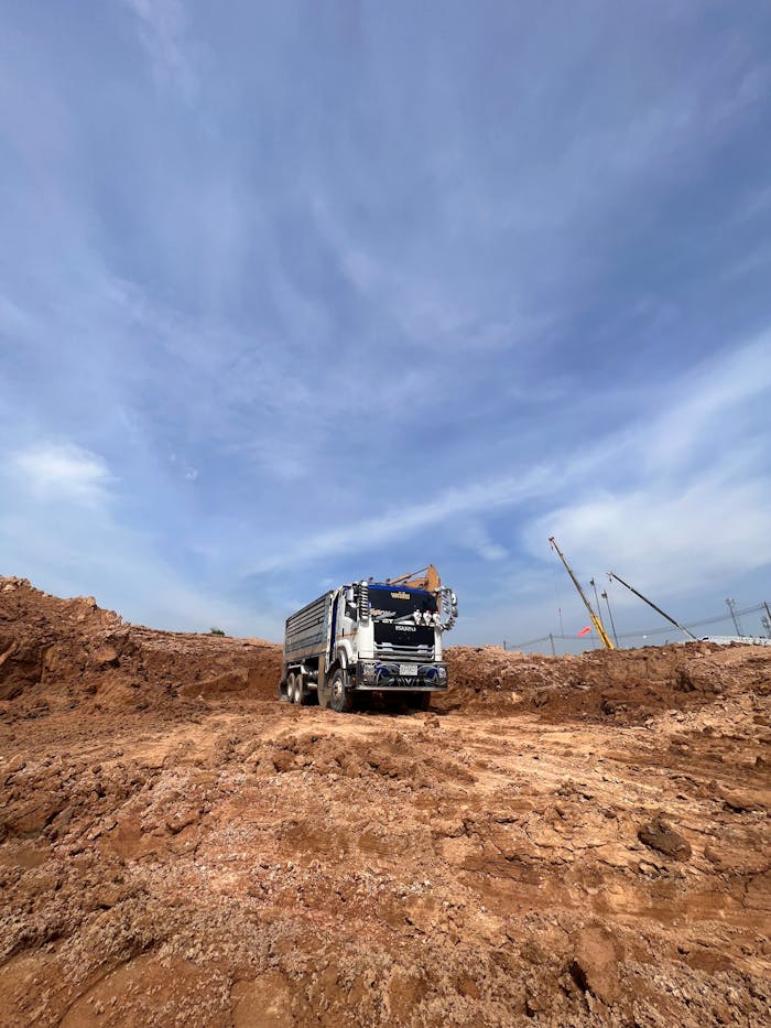 A stationary truck at a construction site under a clear blue sky, showcasing industrial machinery.
