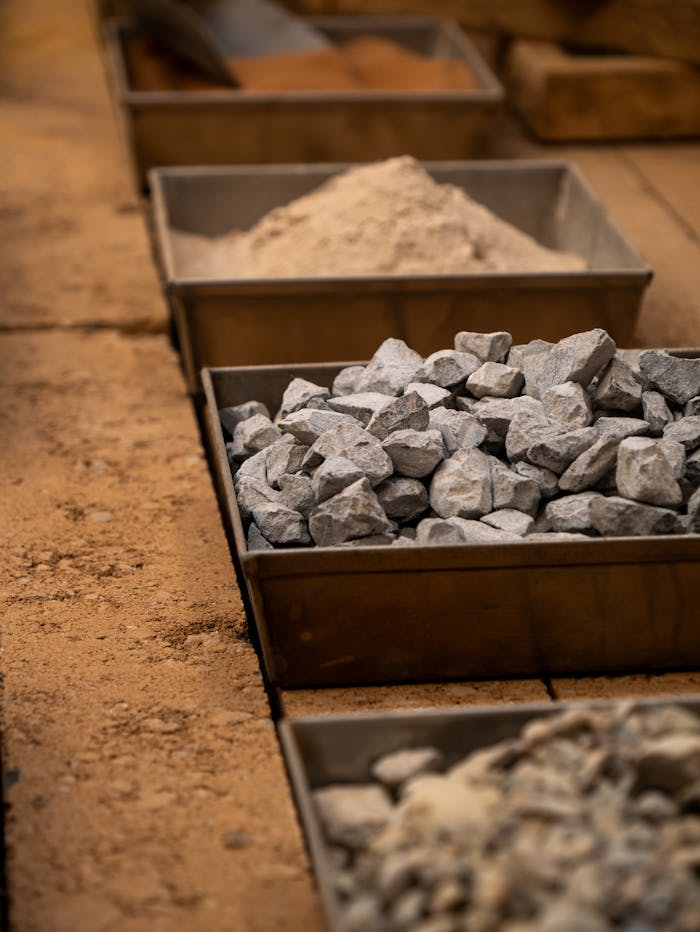 Various construction materials including rocks, and sand in storage boxes.